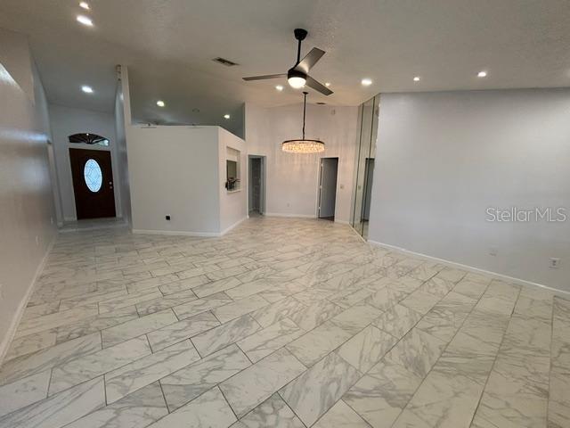 A spacious room features white marble-look tile flooring, a ceiling fan, and a crystal chandelier — 1723 BELL RANCH STREET, BRANDON, FL