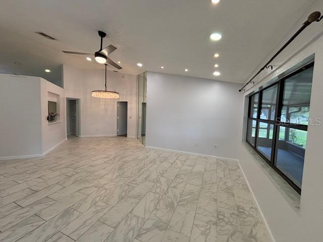 A bright living room features light marble-look tile flooring, recessed lighting, and a ceiling fan — 1723 BELL RANCH STREET, BRANDON, FL