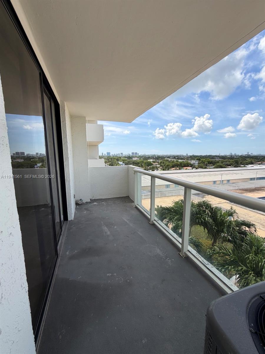 An outdoor balcony features a concrete floor, glass railings, and a view of the city — 13499 Biscayne Blvd # 710, North Miami FL 33181, NORTH MIAMI, FL