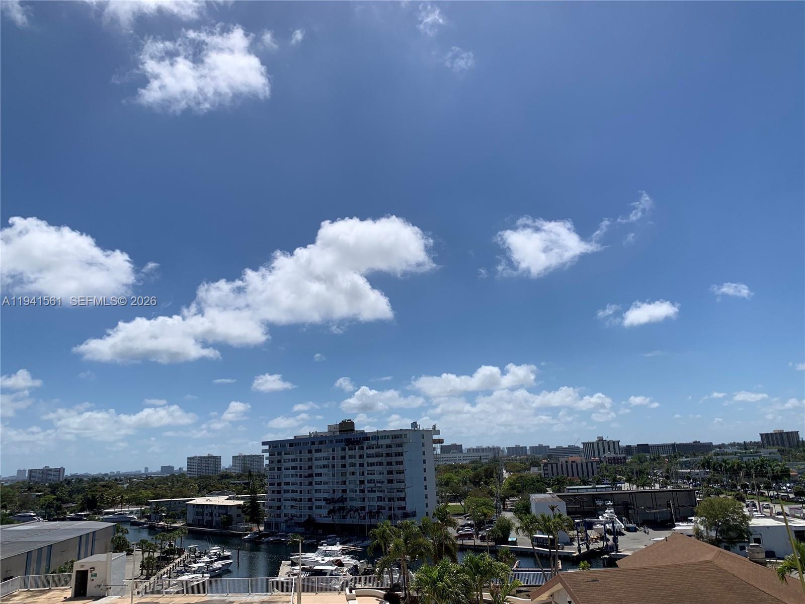 An elevated view shows a marina with boats, residential buildings, and trees under a blue sky — 13499 Biscayne Blvd # 710, North Miami FL 33181, NORTH MIAMI, FL
