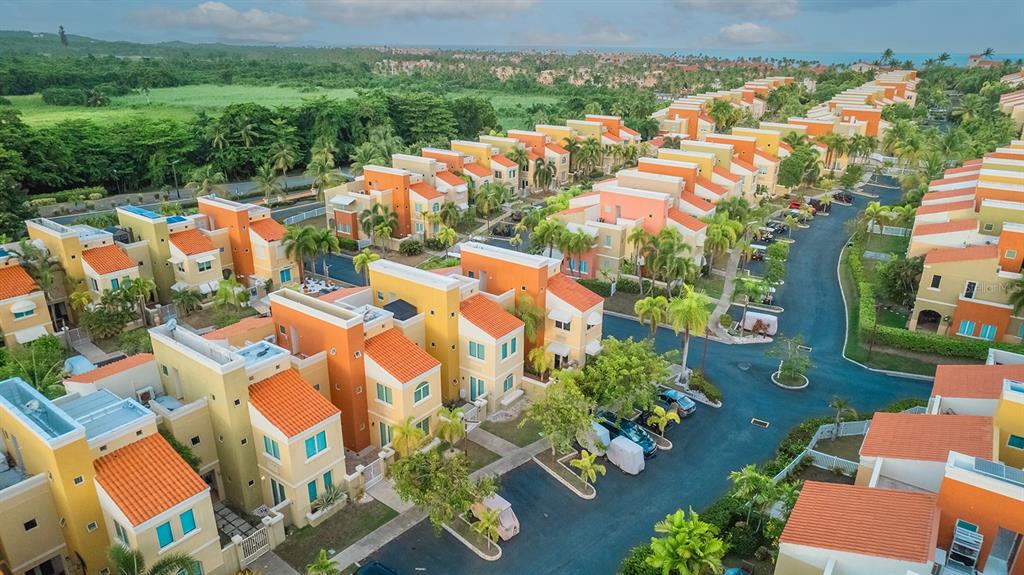 An aerial view shows a neighborhood of colorful townhouses with orange roofs and palm trees — 90 CANDELERO DR UNIT 84, HUMACAO, PR