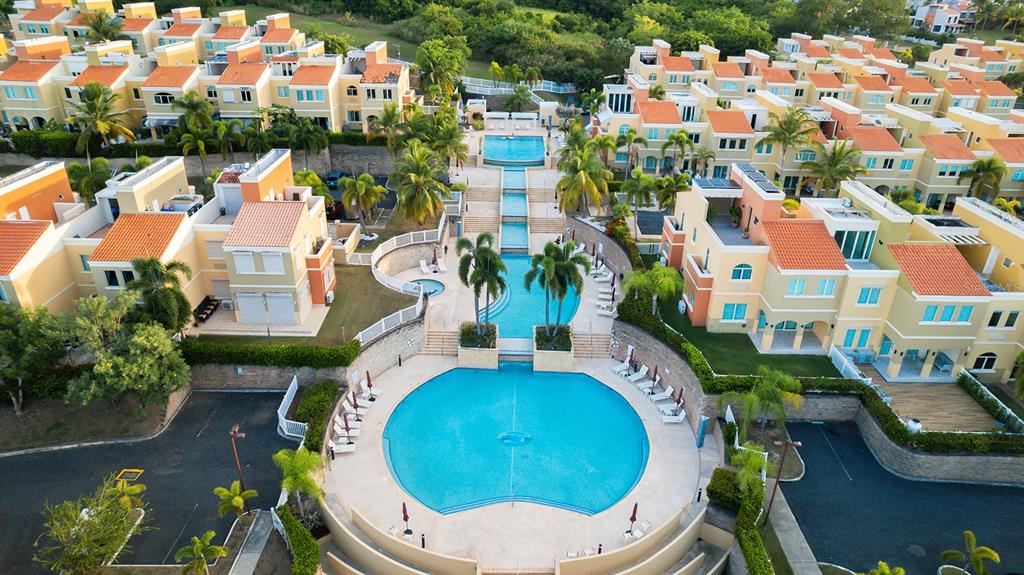 An aerial view shows a multi-level swimming pool complex surrounded by residential townhouses — 90 CANDELERO DR UNIT 84, HUMACAO, PR
