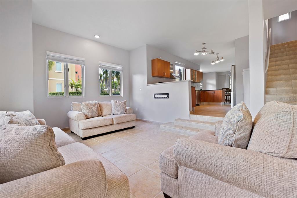 A living room with beige sofas, tile flooring, and steps leading up to a kitchen — 90 CANDELERO DR UNIT 84, HUMACAO, PR