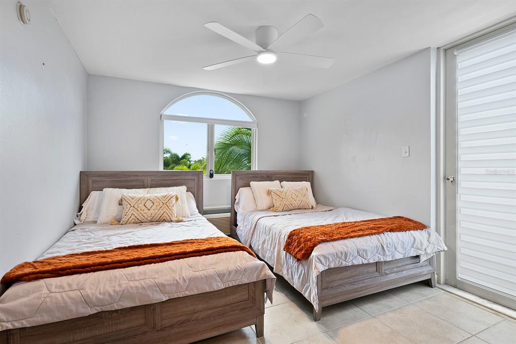 A bedroom features two beds with wooden frames, a ceiling fan, and an arched window — 90 CANDELERO DR UNIT 84, HUMACAO, PR