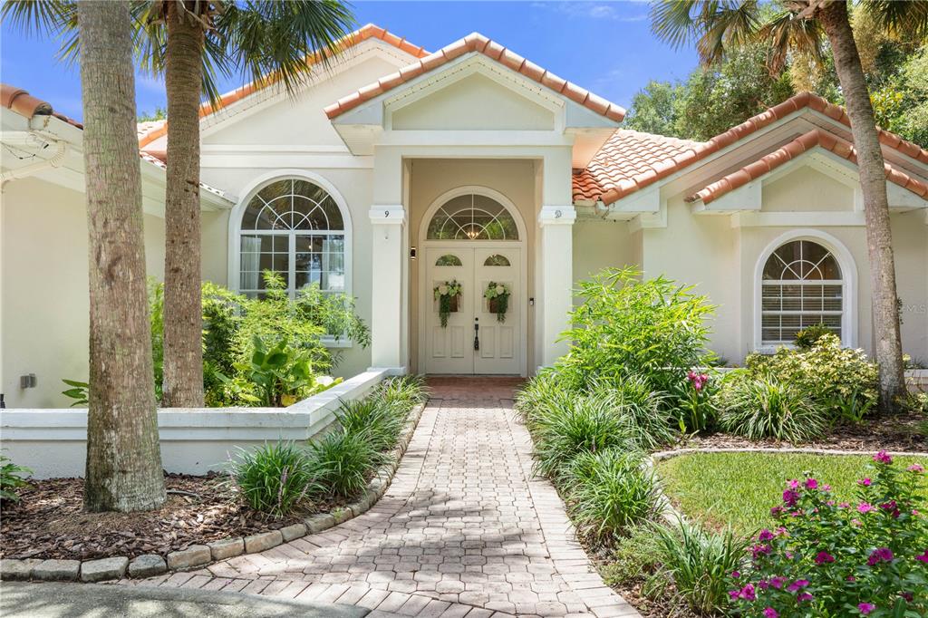 A single-story house with a tiled roof, arched windows, and a brick walkway to the entrance — 9 VIA VERONA, PALM COAST, FL, FL