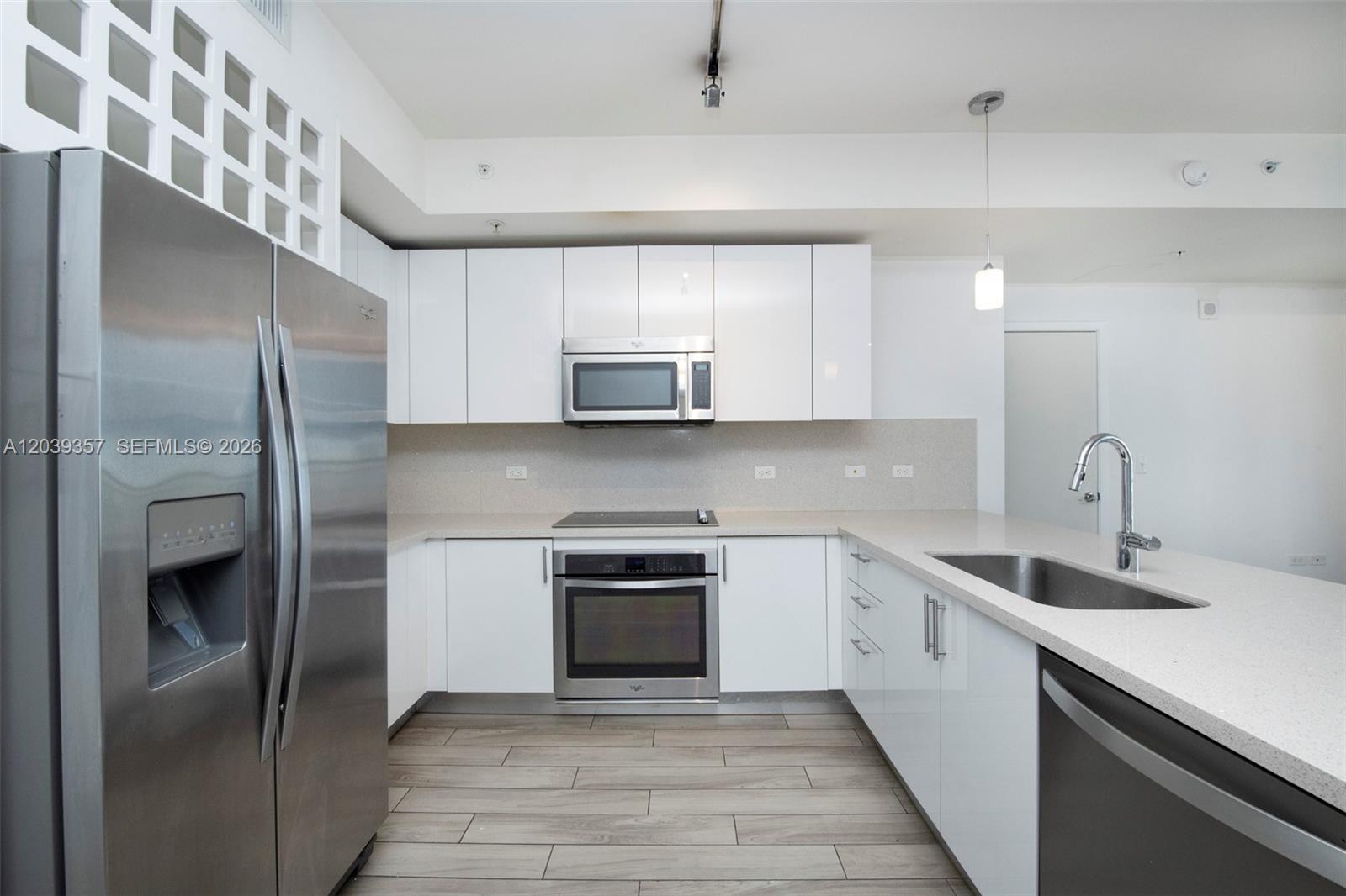 A modern kitchen features white cabinets, stainless steel appliances, and a light-colored stone countertop — 999 SW 1st Ave # 2402, Miami FL 33130, MIAMI, FL
