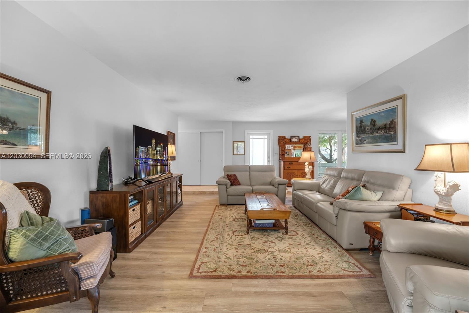 A living room features light wood-look flooring, a beige sofa set, and a television console — 10421 SW 107th St, Miami FL 33176, MIAMI, FL