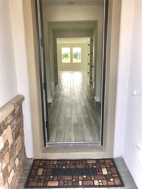 A view through an open front door reveals a hallway with light-colored wood-look tile flooring — 11638 SWEET TANGERINE LANE, TAMPA, FL