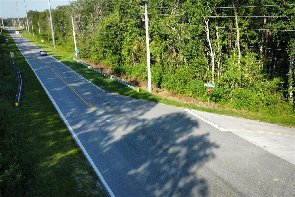 An aerial view shows a paved road with a stop sign and surrounding wooded area — 8915 COUNTY ROAD 44, LEESBURG, FL
