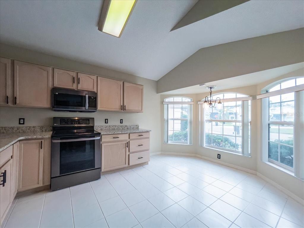 A kitchen with light wood cabinets, stainless steel appliances, and a tiled breakfast nook area — 218 LANGFORD PARK DRIVE, DAVENPORT, FL