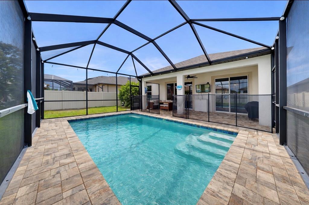 A screened-in patio features a swimming pool with steps and stone pavers — 10322 WINE PRESS AVENUE, RIVERVIEW, FL