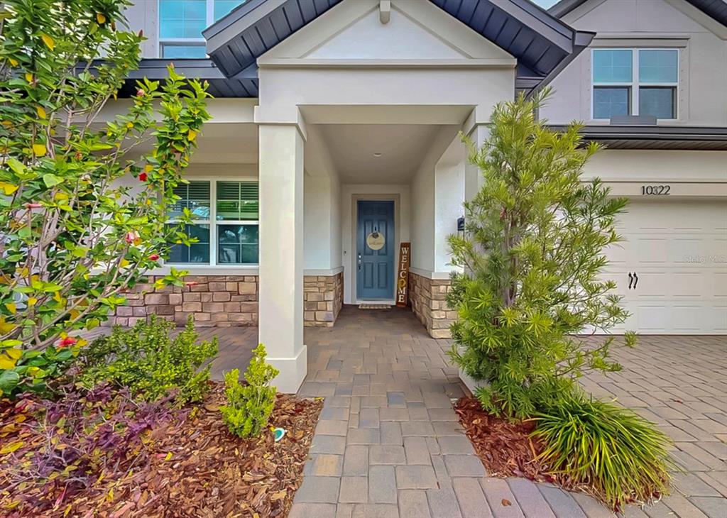 A paved walkway leads to the front entrance of a house with stone accents — 10322 WINE PRESS AVENUE, RIVERVIEW, FL