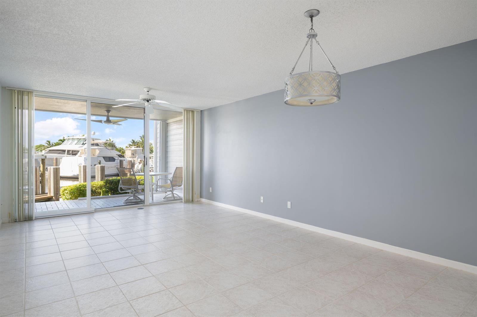 An empty room with light tile floors, a gray accent wall, and a sliding glass door — VERO BEACH, FL