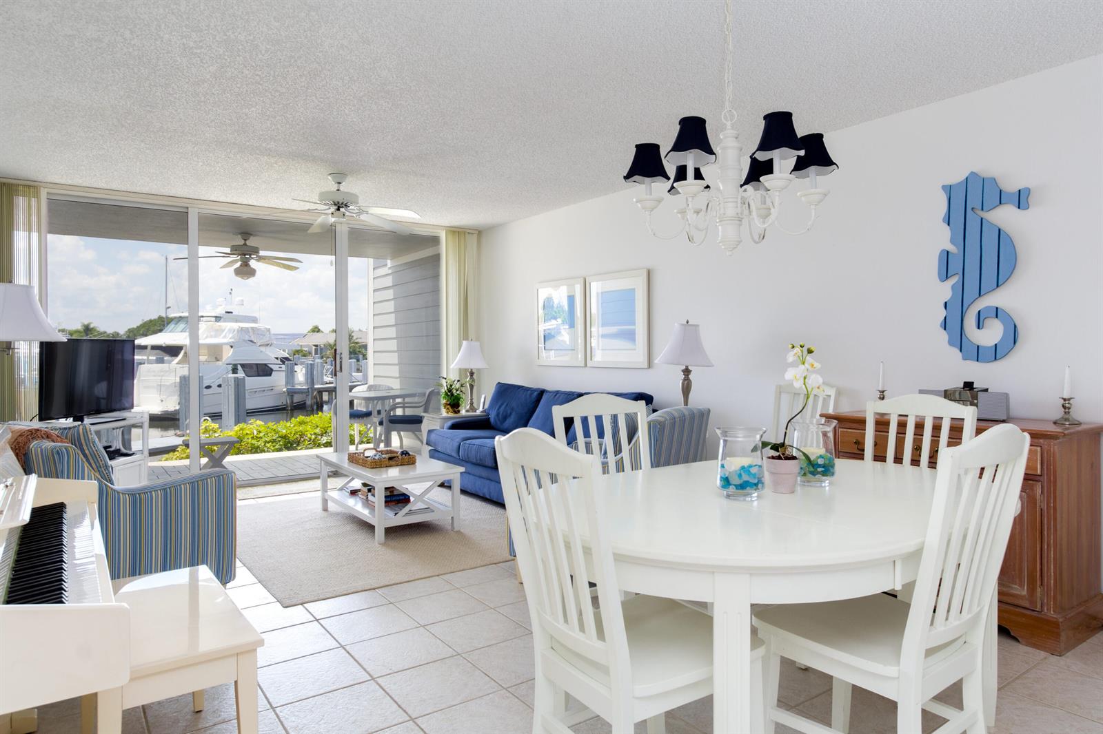 A bright living and dining area features white furniture, a blue sofa, and a marina view — VERO BEACH, FL