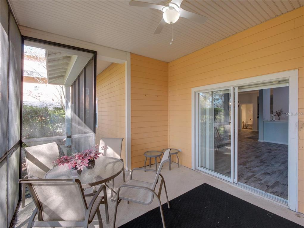 A screened-in patio features a glass-top table, chairs, a ceiling fan, and sliding glass doors — 204 NEW PROVIDENCE UNIT 10104, DAVENPORT, FL