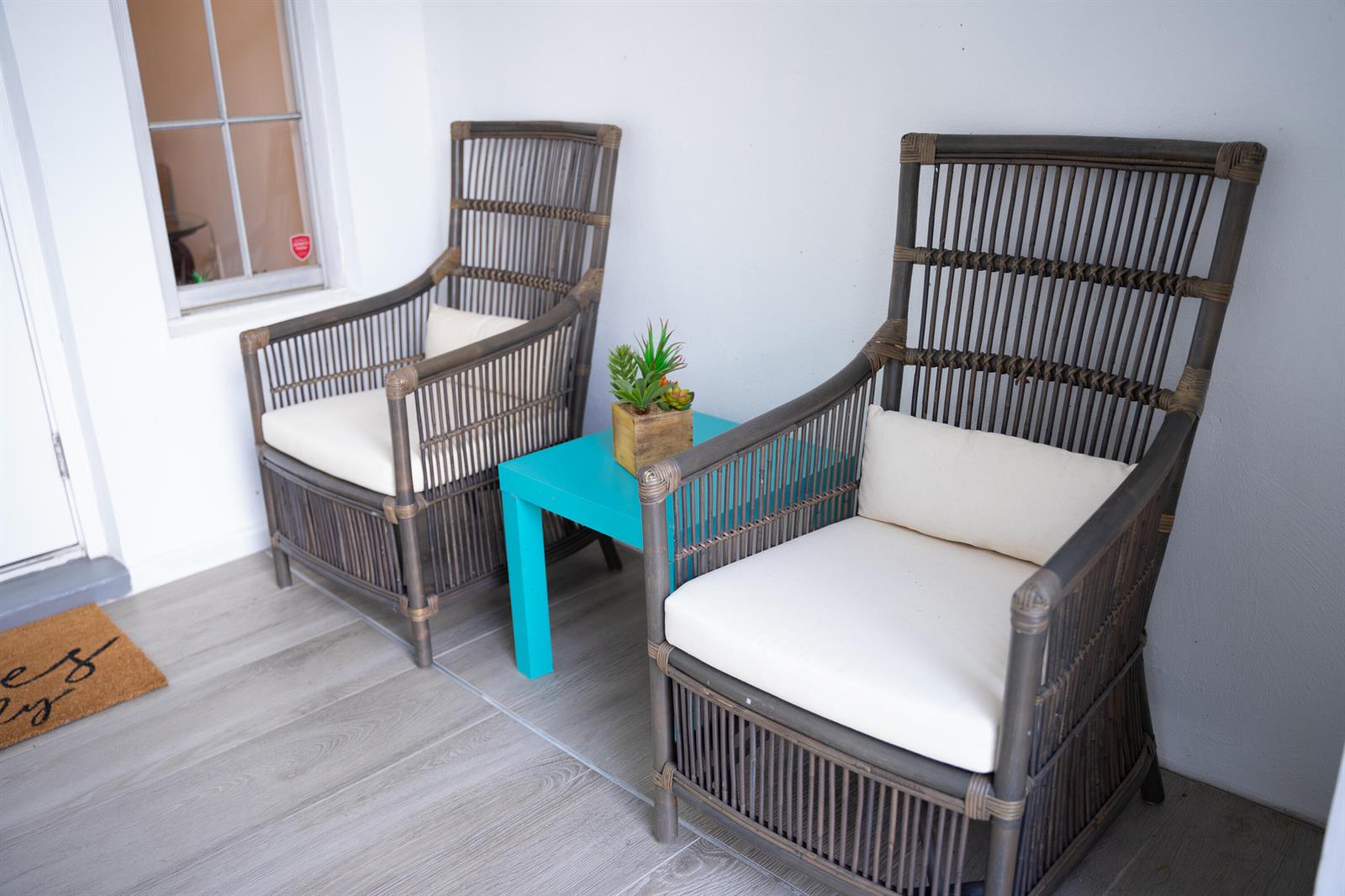 Two wicker chairs with white cushions flank a small teal table on a porch — 1425 Riverside Circle, Wellington FL 33414, WELLINGTON, FL