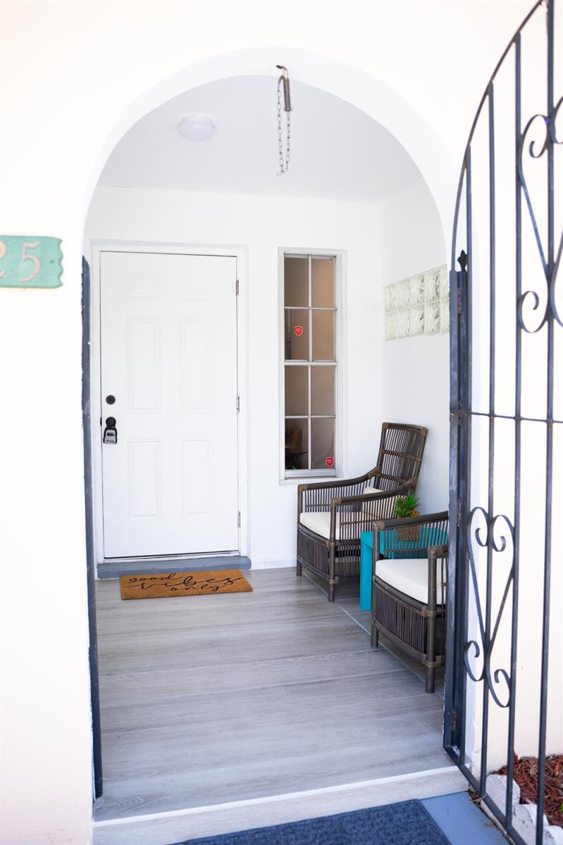 An arched entryway features a white door, gray wood-look flooring, and two wicker chairs — 1425 Riverside Circle, Wellington FL 33414, WELLINGTON, FL