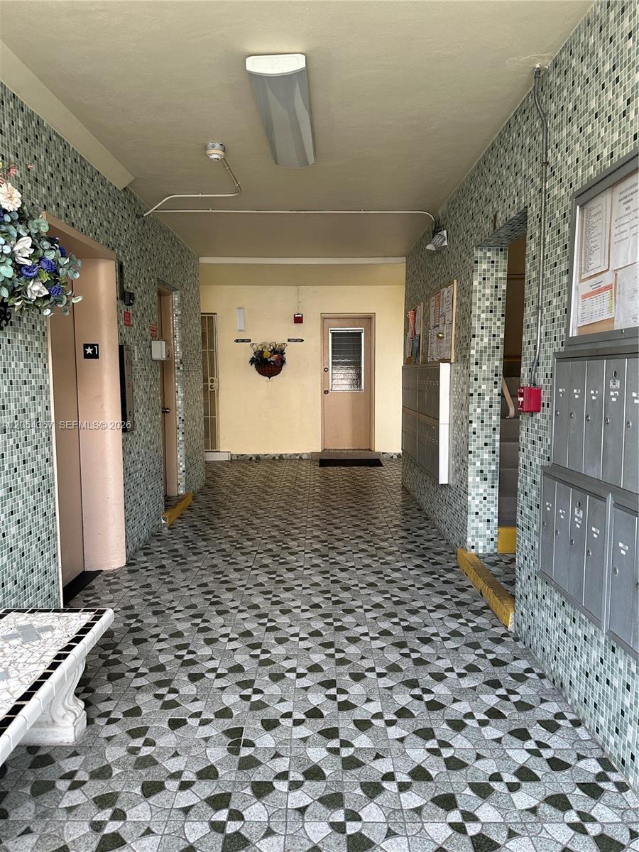 A tiled hallway features an elevator, mailboxes, and a door leading to the building exterior — 17050 NE 14th Ave # 110, Miami FL 33162, MIAMI, FL