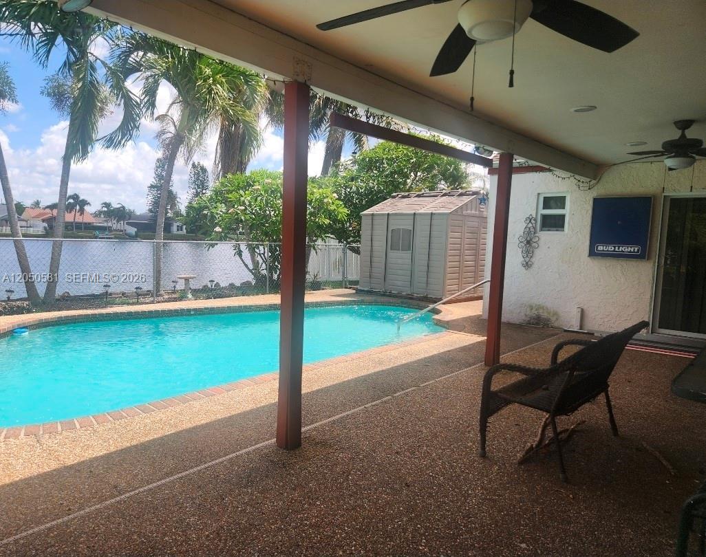 A covered patio overlooks a swimming pool, a storage shed, and a fenced backyard — 11711 NW 35th St, Sunrise FL 33323, SUNRISE, FL
