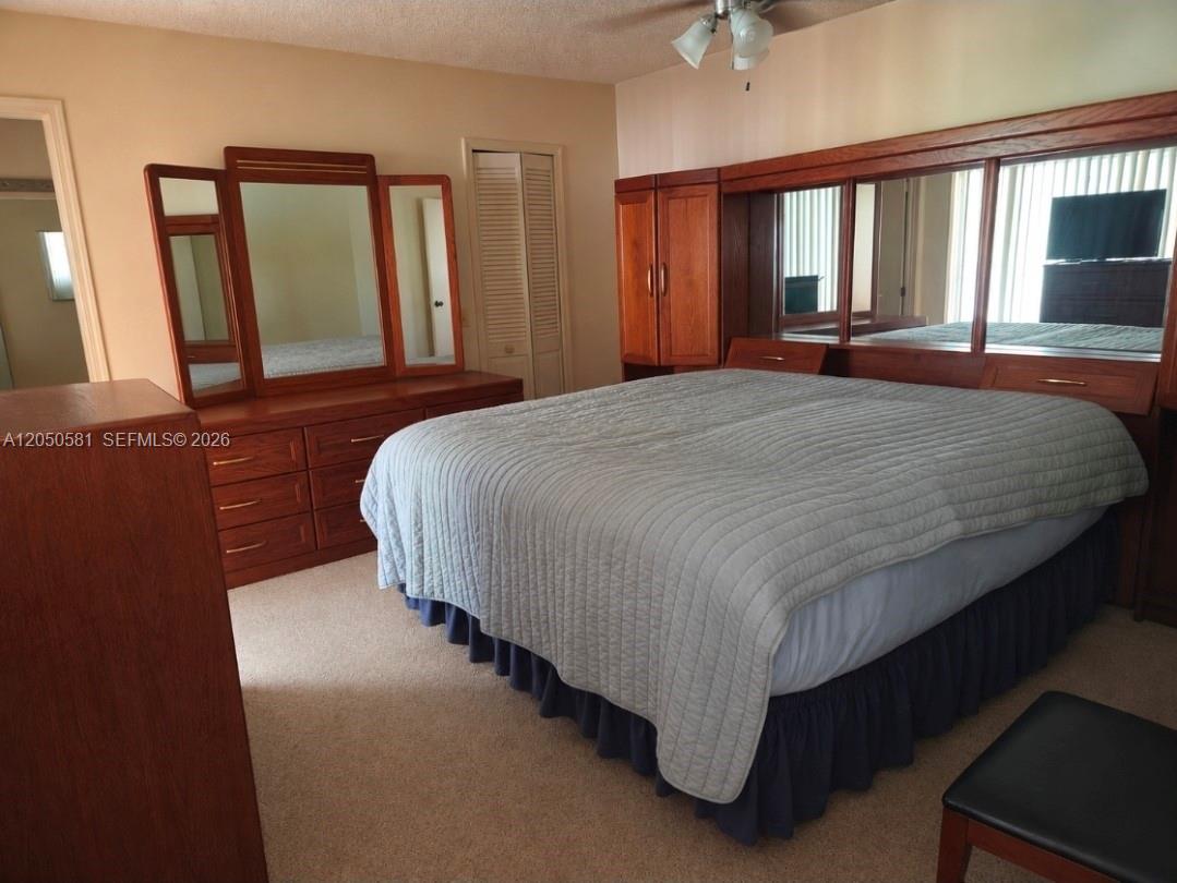 A bedroom features a large wooden headboard with built-in mirrors, a matching dresser, and carpeted flooring — 11711 NW 35th St, Sunrise FL 33323, SUNRISE, FL