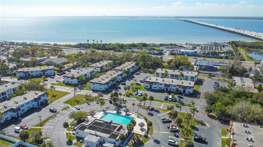 An aerial view shows an apartment complex with a swimming pool near a large bay — 215 S MCMULLEN BOOTH ROAD UNIT 182, CLEARWATER, FL