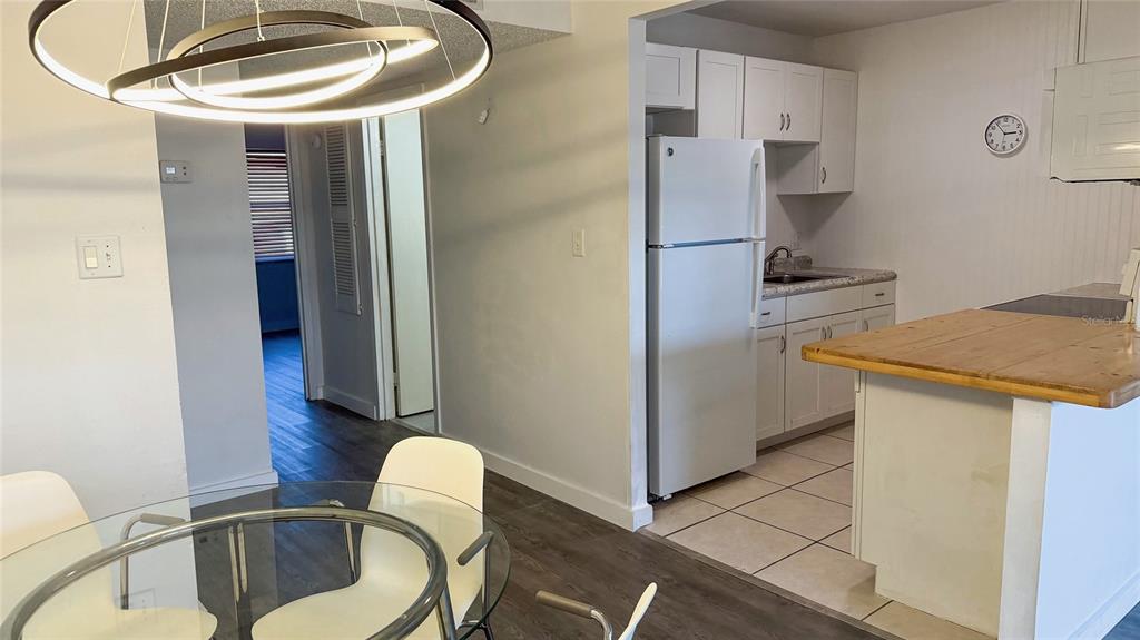 A dining area with a modern chandelier overlooks a kitchen with white cabinets and appliances — 215 S MCMULLEN BOOTH ROAD UNIT 182, CLEARWATER, FL