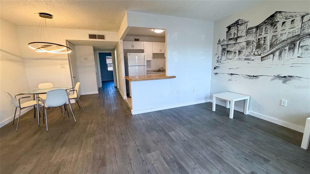 An open-concept dining and living area features gray wood-look flooring and a wall mural — 215 S MCMULLEN BOOTH ROAD UNIT 182, CLEARWATER, FL