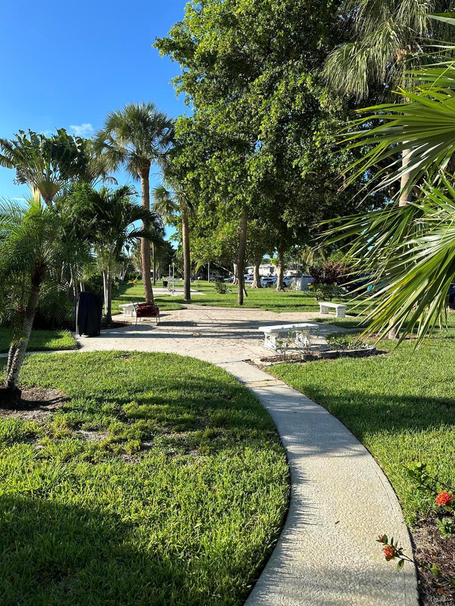 A paved walkway winds through a grassy park area with palm trees and stone benches — 3801 NE 22nd Terrace # 11, Lighthouse Point FL 33064, LIGHTHOUSE POINT, FL