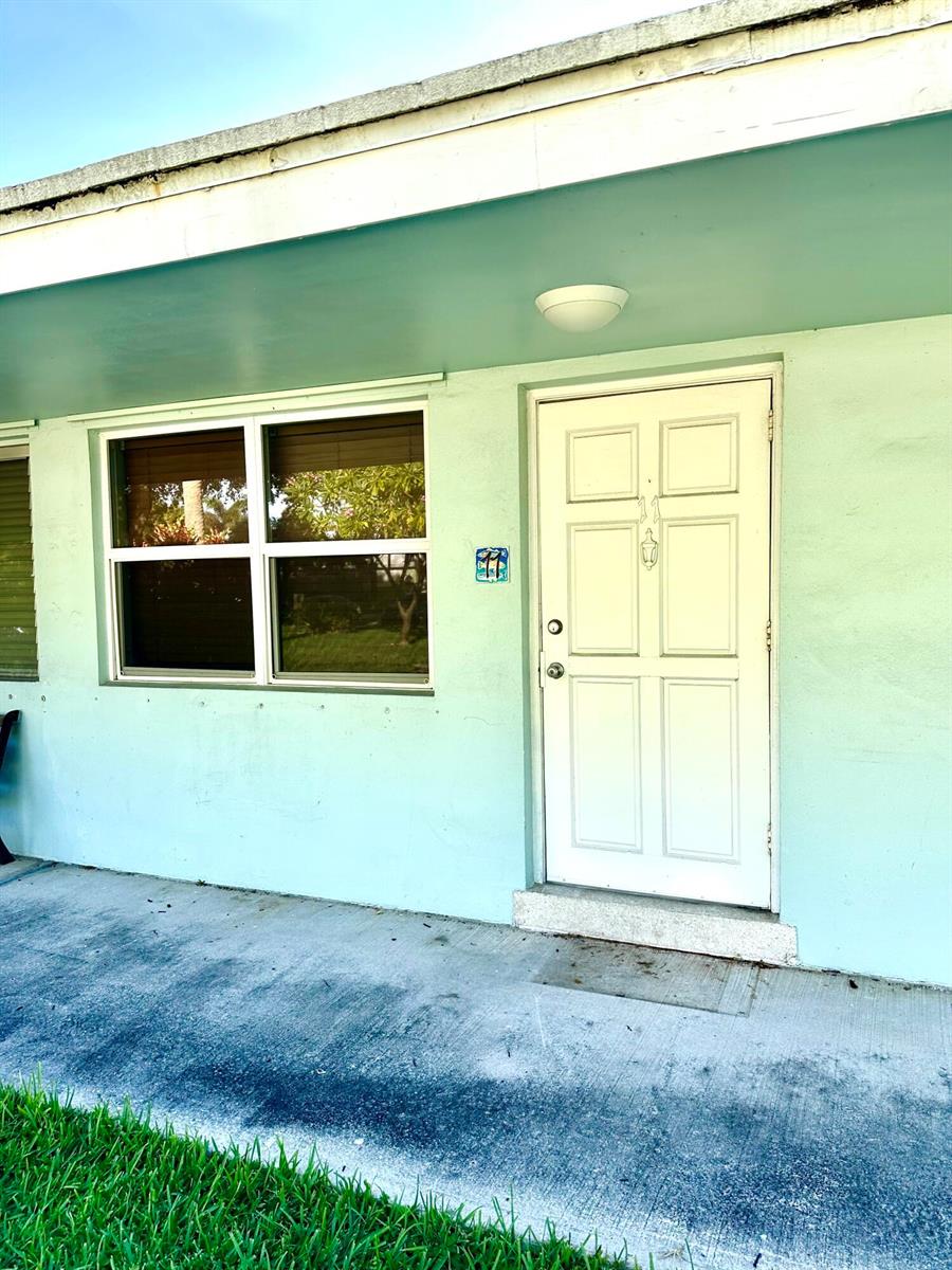 A light green exterior wall features a white front door and a large window — 3801 NE 22nd Terrace # 11, Lighthouse Point FL 33064, LIGHTHOUSE POINT, FL