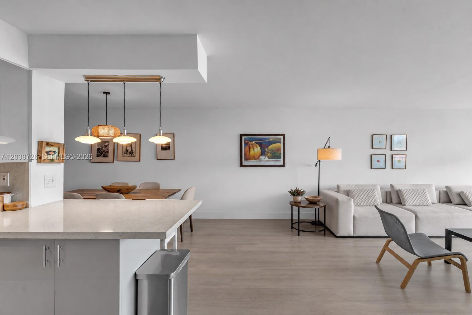An open-concept living and dining area features light wood floors, neutral furniture, and pendant lighting — 150 Ocean Lane Dr # 7C, Key Biscayne FL 33149, KEY BISCAYNE, FL