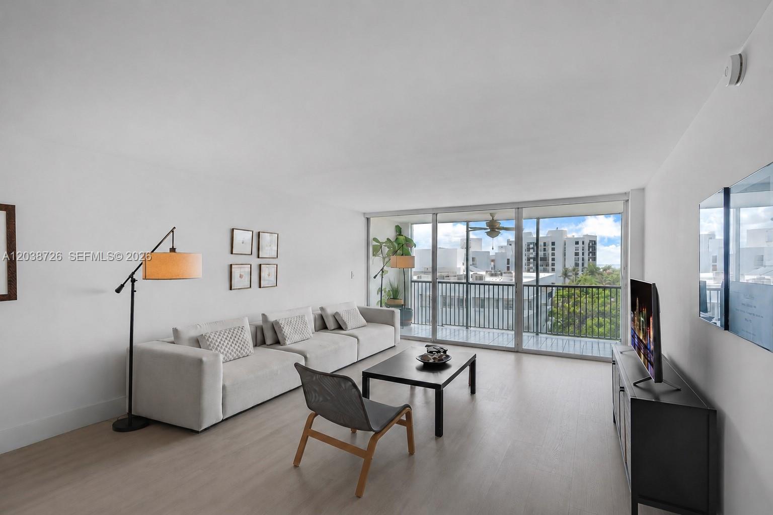 A modern living room features a light gray sofa, coffee table, and balcony access — 150 Ocean Lane Dr # 7C, Key Biscayne FL 33149, KEY BISCAYNE, FL