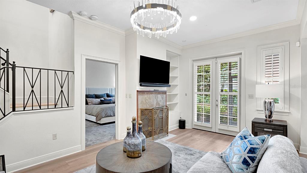 A living room features a fireplace, a chandelier, and a doorway leading to a bedroom — 1223 COUNTRY CLUB OAKS CIRCLE, ORLANDO, FL