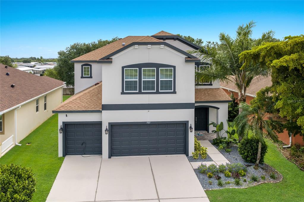 A two-story house with a three-car garage, white stucco walls, and a brown shingled roof — 5815 ARBOR WOOD COURT, BRADENTON, FL