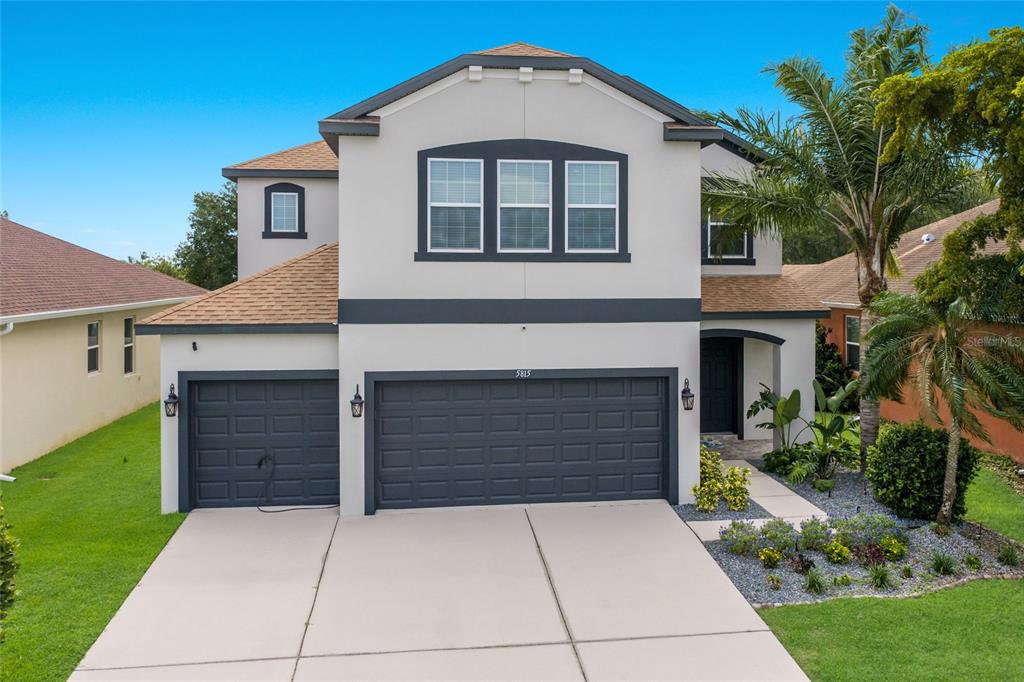 A two-story house with a three-car garage, light stucco exterior, and dark trim — 5815 ARBOR WOOD COURT, BRADENTON, FL