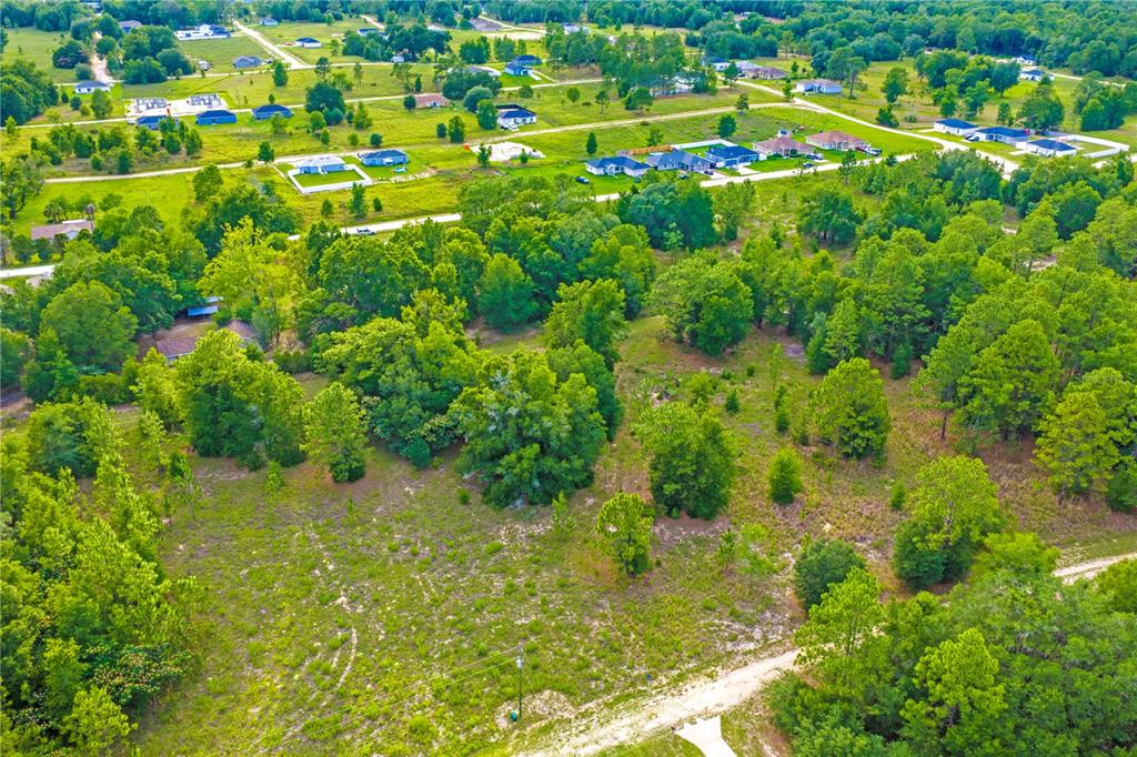 An aerial view shows a grassy, partially wooded lot with a dirt road and nearby houses — 000 SW 146 COURT, OCALA, FL