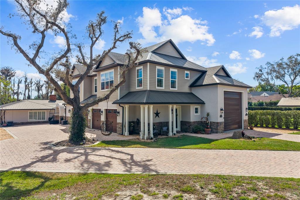 A two-story house with a metal roof, stone accents, and a paved driveway — 11002 LAKE BUTLER BOULEVARD, WINDERMERE, FL
