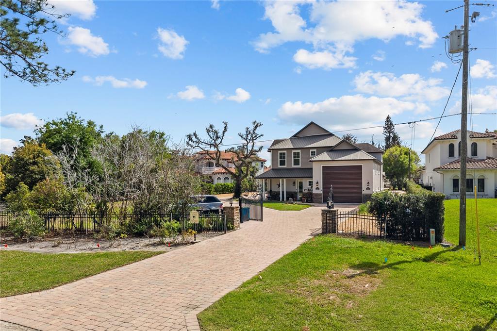 A two-story house with a paved driveway and metal roof sits behind a gated entrance — 11002 LAKE BUTLER BOULEVARD, WINDERMERE, FL