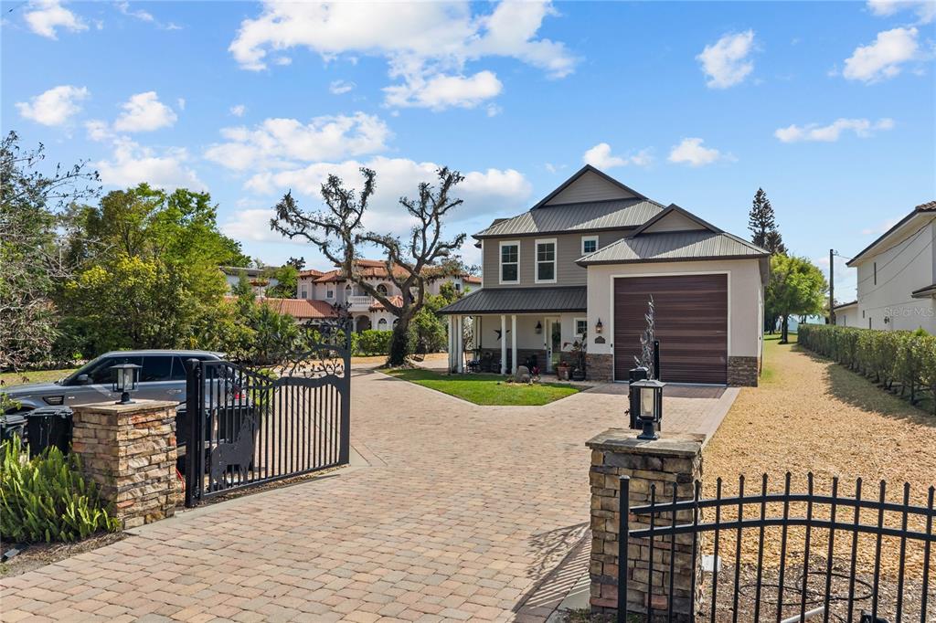 A two-story house with a paved driveway, metal roof, and gated entrance — 11002 LAKE BUTLER BOULEVARD, WINDERMERE, FL