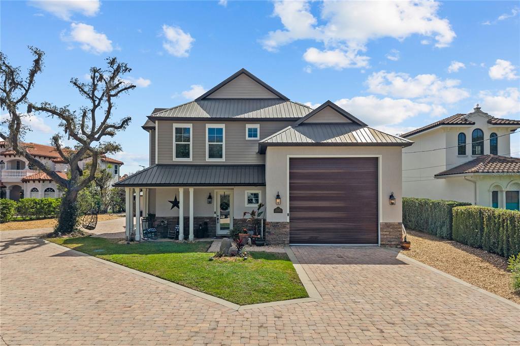 A two-story house with a metal roof, a single-car garage, and a brick-paved driveway — 11002 LAKE BUTLER BOULEVARD, WINDERMERE, FL