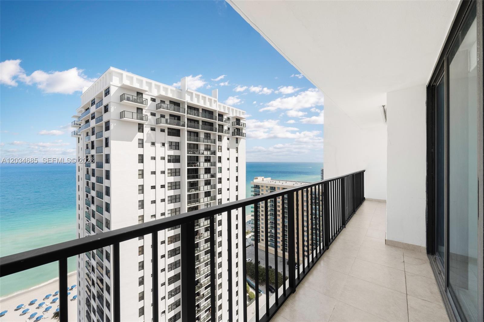 A balcony with a black metal railing overlooks the ocean and a tall residential building — 2401 S Ocean Dr # 2402, Hollywood FL 33019, HOLLYWOOD, FL