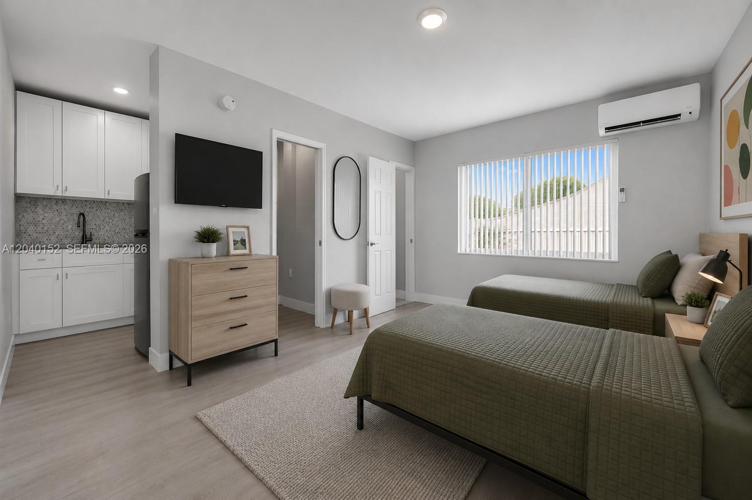 A bedroom with two twin beds, a small kitchenette, and light wood flooring — 6647 SW 59th Pl # 202, South Miami FL 33143, SOUTH MIAMI, FL