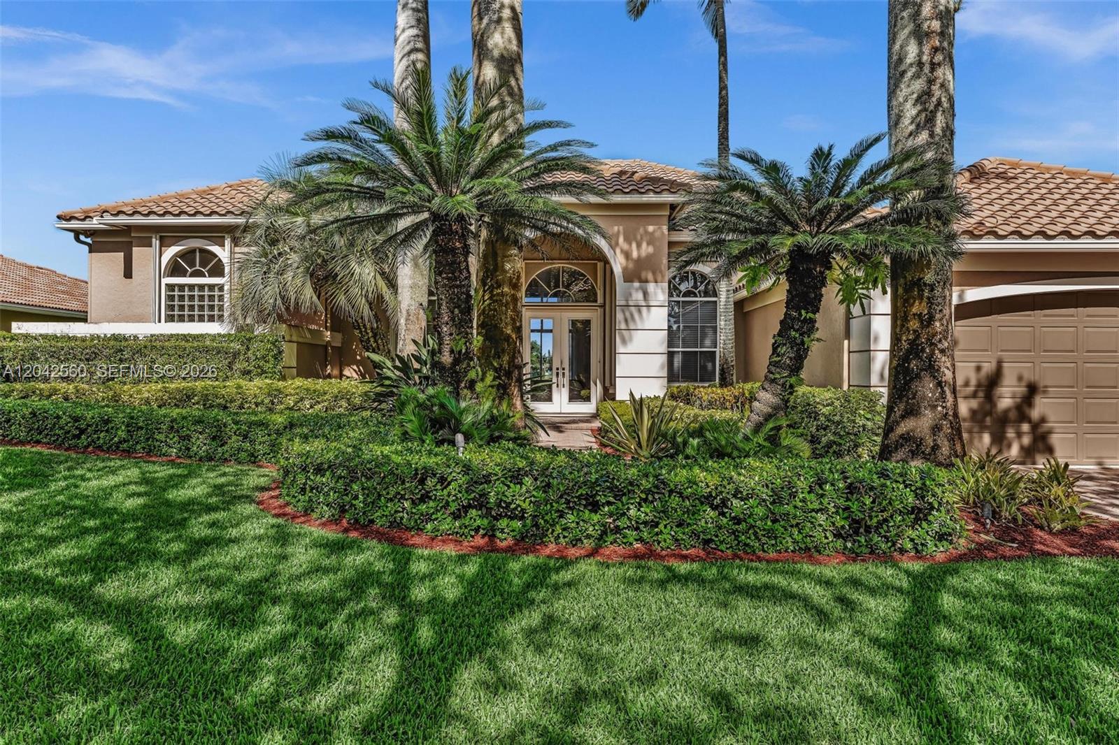 A single-story house with a tiled roof, arched entryway, and palm trees in the front yard — 2733 Meadowood Dr, Weston FL 33332, WESTON, FL