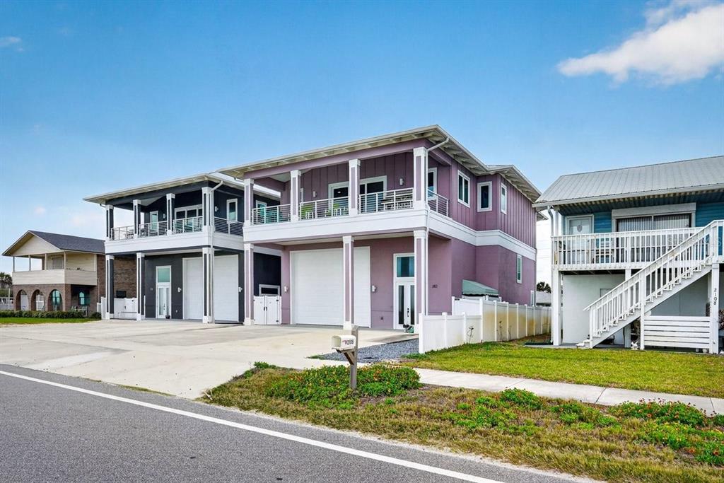 A purple two-story house with a large garage and a balcony stands beside other homes — 2112 S OCEAN SHORE BOULEVARD, FLAGLER BEACH, FL