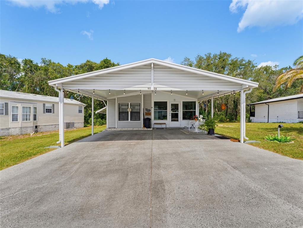 A single-story manufactured home features a large concrete driveway and an attached white carport — 9528 GRAY FOX DRIVE, WEEKI WACHEE, FL