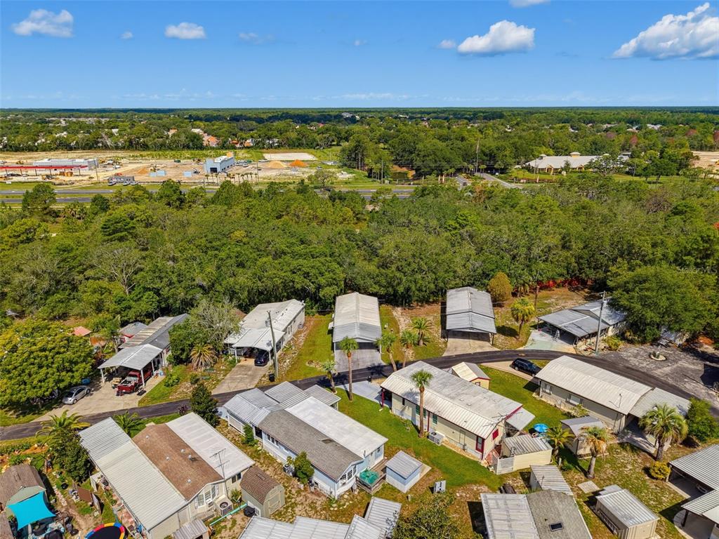 An aerial view shows several mobile homes with metal roofs situated in a wooded area — 9528 GRAY FOX DRIVE, WEEKI WACHEE, FL