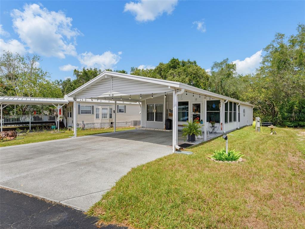 A light-colored mobile home features a large attached carport and a screened-in front porch — 9528 GRAY FOX DRIVE, WEEKI WACHEE, FL