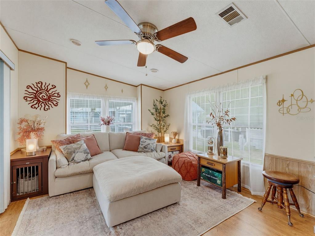 A living room features a beige sectional sofa, a ceiling fan, and wood-look flooring — 9528 GRAY FOX DRIVE, WEEKI WACHEE, FL