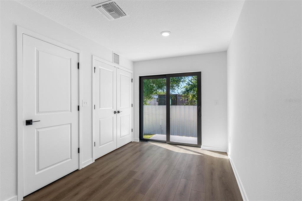 A room with wood-look flooring, two white doors, and a sliding glass door to outside — 620 BLACKTHORN DRIVE, LAKELAND, FL