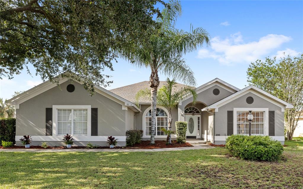 A single-story gray house with a palm tree, arched window, and a front lawn — 496 TERRANOVA STREET, WINTER HAVEN, FL