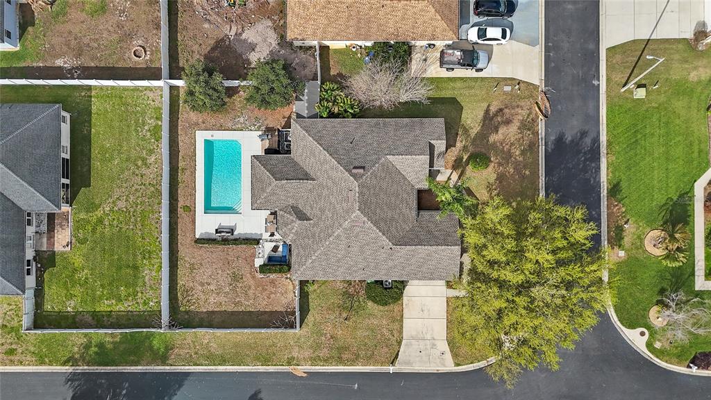 An aerial view shows a house with a swimming pool, driveway, and surrounding lawn — 496 TERRANOVA STREET, WINTER HAVEN, FL